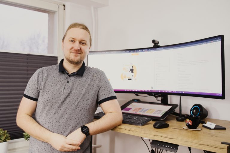 aswebdesign Mężczyzna stojący przed biurkiem z dwoma monitorami, pracujący na Stronach internetowych.